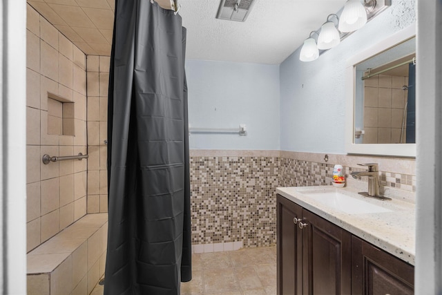 5961 NW 61st Ave Unit 203, Tamarac, FL 33319 - bathroom with tile walls, vanity, a shower with curtain, a textured ceiling, and wainscoting
