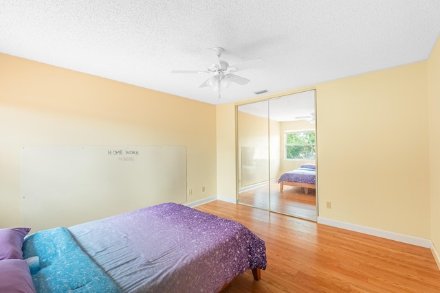 2322 SW Olympic Club Ter, Palm City, FL 34990 - bedroom featuring light wood finished floors, a textured ceiling, a ceiling fan, and a closet