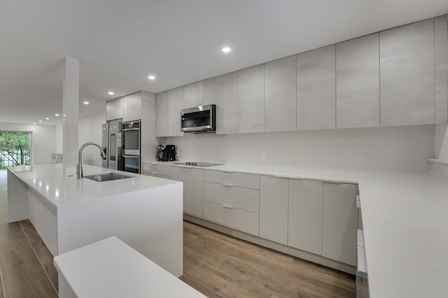 2845 SW 22nd Ave Unit 2070, Delray Beach, FL 33445 - kitchen featuring appliances with stainless steel finishes, modern cabinets, wood finished floors, a kitchen island with sink, and light countertops