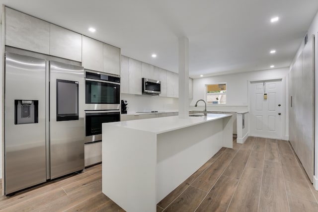 2845 SW 22nd Ave Unit 2070, Delray Beach, FL 33445 - kitchen featuring appliances with stainless steel finishes, modern cabinets, light countertops, light wood-style flooring, and a kitchen island with sink