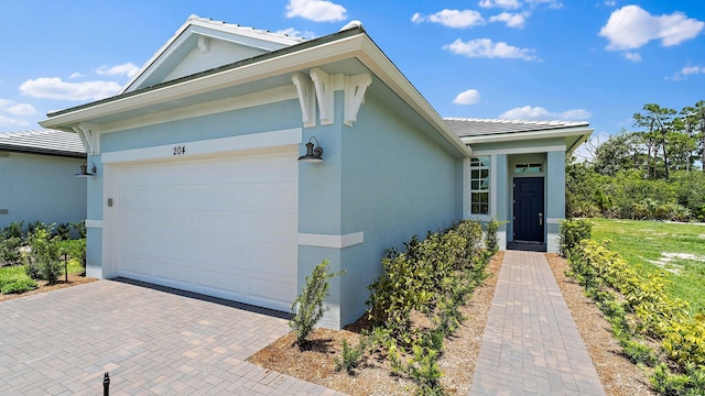204 SE Via Sangro, Port Saint Lucie, FL 34952 - view of front facade with a garage, a tiled roof, decorative driveway, and stucco siding