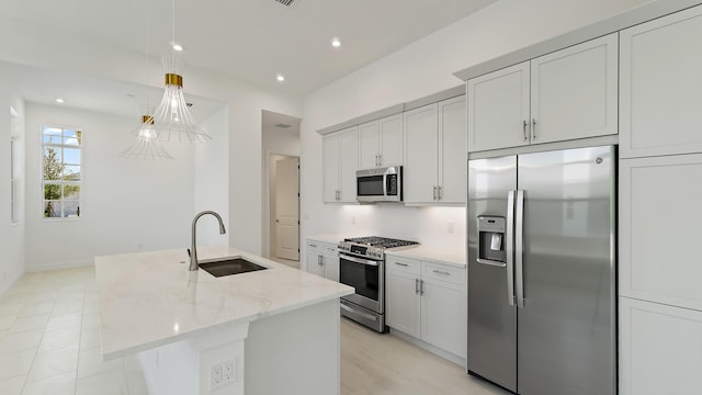 204 SE Via Sangro, Port Saint Lucie, FL 34952 - kitchen with stainless steel appliances, light stone countertops, an island with sink, recessed lighting, and decorative light fixtures