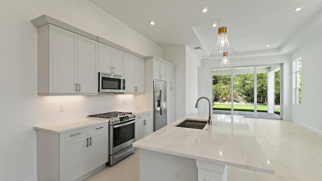 204 SE Via Sangro, Port Saint Lucie, FL 34952 - kitchen featuring appliances with stainless steel finishes, recessed lighting, a center island with sink, light stone counters, and a chandelier
