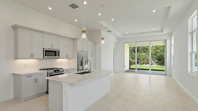 204 SE Via Sangro, Port Saint Lucie, FL 34952 - kitchen with stainless steel appliances, a center island with sink, a raised ceiling, pendant lighting, and open floor plan