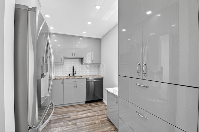 102 Normandy Ln Unit C, Delray Beach, FL 33484 - kitchen with appliances with stainless steel finishes, light wood finished floors, backsplash, modern cabinets, and recessed lighting