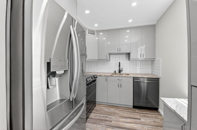 102 Normandy Ln Unit C, Delray Beach, FL 33484 - kitchen with appliances with stainless steel finishes, light wood-style flooring, backsplash, recessed lighting, and light stone countertops