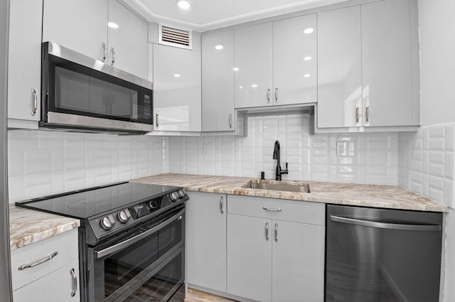 102 Normandy Ln Unit C, Delray Beach, FL 33484 - kitchen featuring stainless steel appliances, tasteful backsplash, and light stone counters