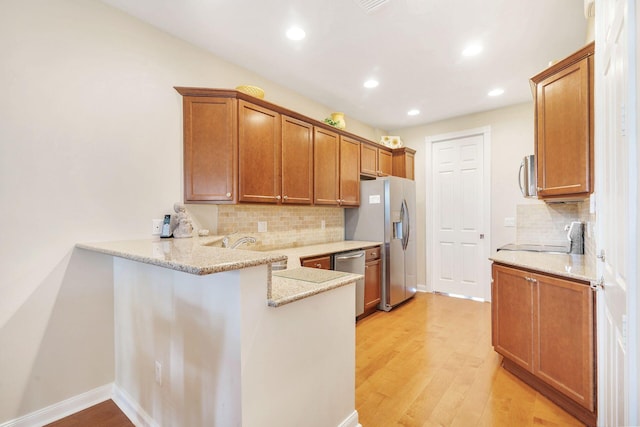 3330 W Mallory Blvd, Jupiter, FL 33458 - kitchen with appliances with stainless steel finishes, tasteful backsplash, a peninsula, light wood-style flooring, and recessed lighting