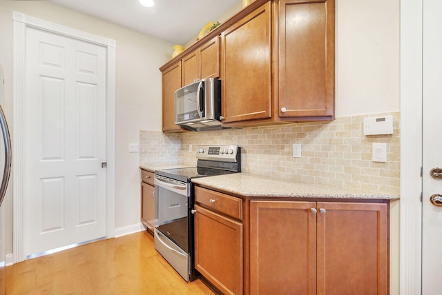 3330 W Mallory Blvd, Jupiter, FL 33458 - kitchen with stainless steel appliances, light wood-style floors, brown cabinetry, backsplash, and recessed lighting