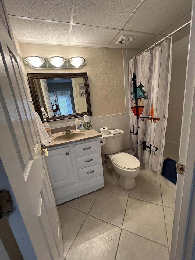 291 Saxony Unit G, Delray Beach, FL 33446 - bathroom featuring a drop ceiling, vanity, tile patterned floors, tile walls, and a textured wall
