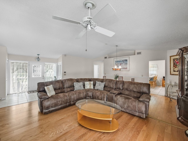 1680 SW Belgrave Ter, Stuart, FL 34997 - living room with light wood finished floors, a ceiling fan, vaulted ceiling, and a textured ceiling