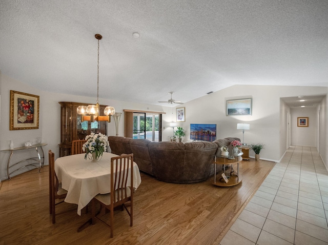 1680 SW Belgrave Ter, Stuart, FL 34997 - dining space featuring a textured ceiling, vaulted ceiling, light wood-style flooring, a chandelier, and a ceiling fan