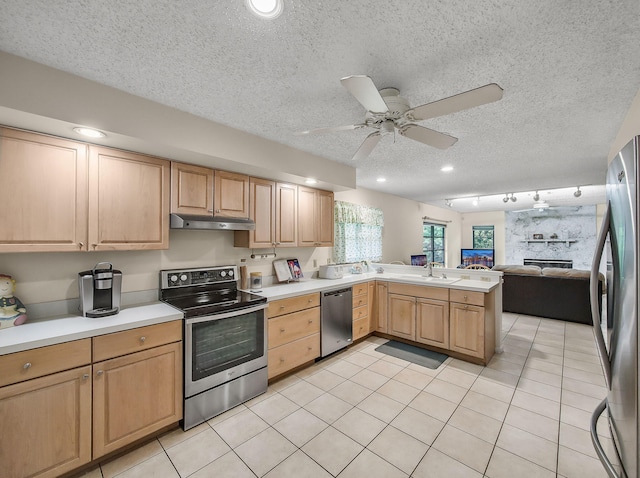 1680 SW Belgrave Ter, Stuart, FL 34997 - kitchen with appliances with stainless steel finishes, under cabinet range hood, light brown cabinetry, open floor plan, and a textured ceiling
