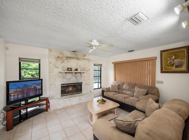 1680 SW Belgrave Ter, Stuart, FL 34997 - living room featuring plenty of natural light, a textured ceiling, a ceiling fan, a premium fireplace, and light tile patterned flooring