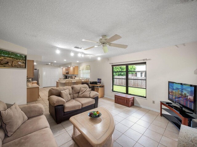 1680 SW Belgrave Ter, Stuart, FL 34997 - living room featuring light tile patterned floors, a ceiling fan, and a textured ceiling