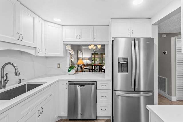 14721 Bonaire Blvd Unit 101, Delray Beach, FL 33446 - kitchen featuring appliances with stainless steel finishes, white cabinets, a chandelier, and light stone counters