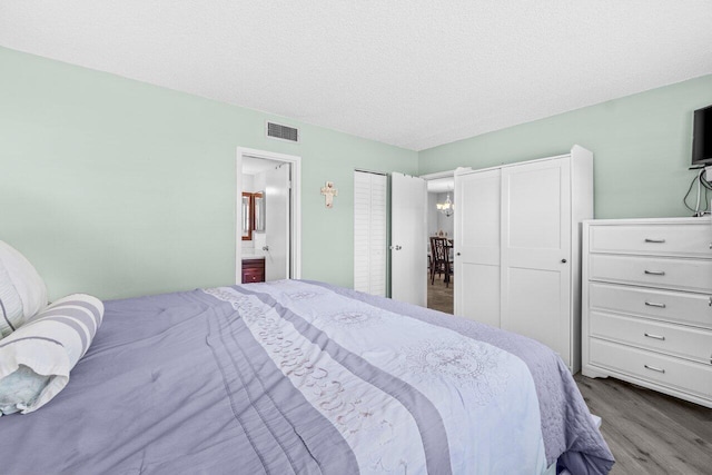 14721 Bonaire Blvd Unit 101, Delray Beach, FL 33446 - bedroom with wood finished floors, ensuite bathroom, and a textured ceiling