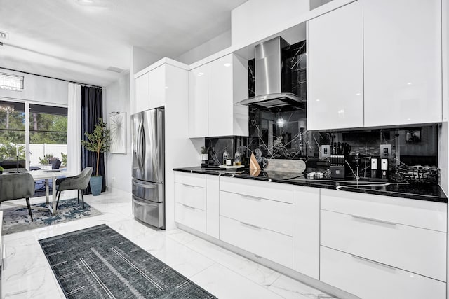 5476 NW Cambo Ct, Port Saint Lucie, FL 34986 - kitchen featuring modern cabinets, stainless steel refrigerator with ice dispenser, wall chimney exhaust hood, dark countertops, and white cabinetry
