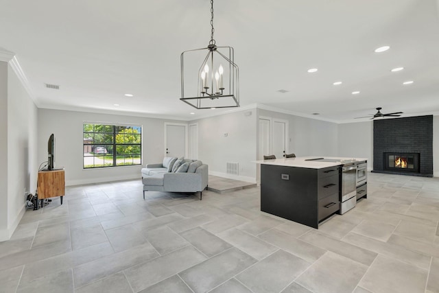 208 SW Langfield Ave, Port Saint Lucie, FL 34984 - kitchen with open floor plan, crown molding, dark cabinets, ceiling fan, and a center island