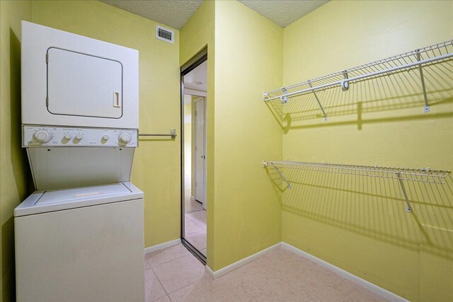 14 Plantation Dr Unit 105, Vero Beach, FL 32966 - washroom with stacked washing machine and dryer and tile patterned flooring