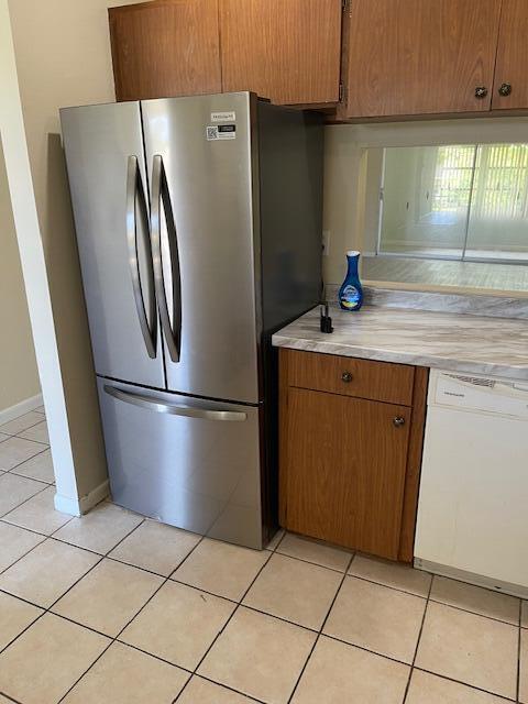 1900 S Kanner Hwy Unit 5-206, Stuart, FL 34994 - kitchen with freestanding refrigerator, dishwasher, light countertops, light tile patterned floors, and brown cabinetry