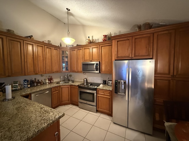 9828 Boca Gardens Trl Unit D, Boca Raton, FL 33496 - kitchen with appliances with stainless steel finishes, brown cabinets, vaulted ceiling, light tile patterned flooring, and a textured ceiling