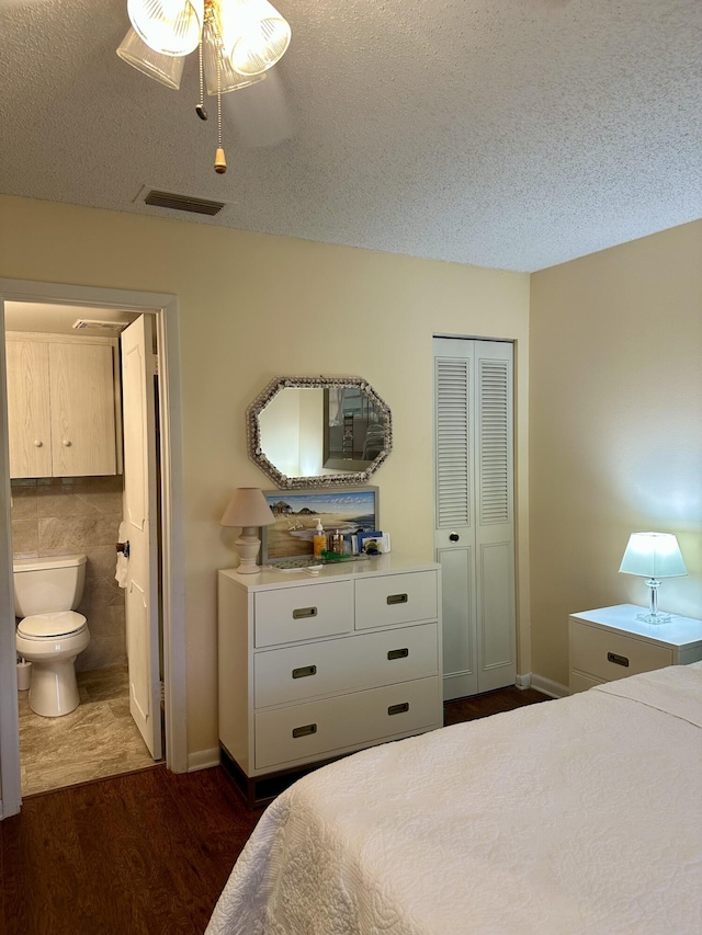 1957 SW Palm City Rd Unit B, Stuart, FL 34994 - bedroom featuring dark wood-style flooring, a textured ceiling, ensuite bathroom, and a closet
