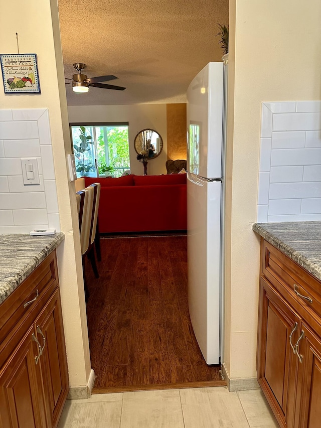 1957 SW Palm City Rd Unit B, Stuart, FL 34994 - kitchen with freestanding refrigerator, ceiling fan, stone countertops, a textured ceiling, and brown cabinets