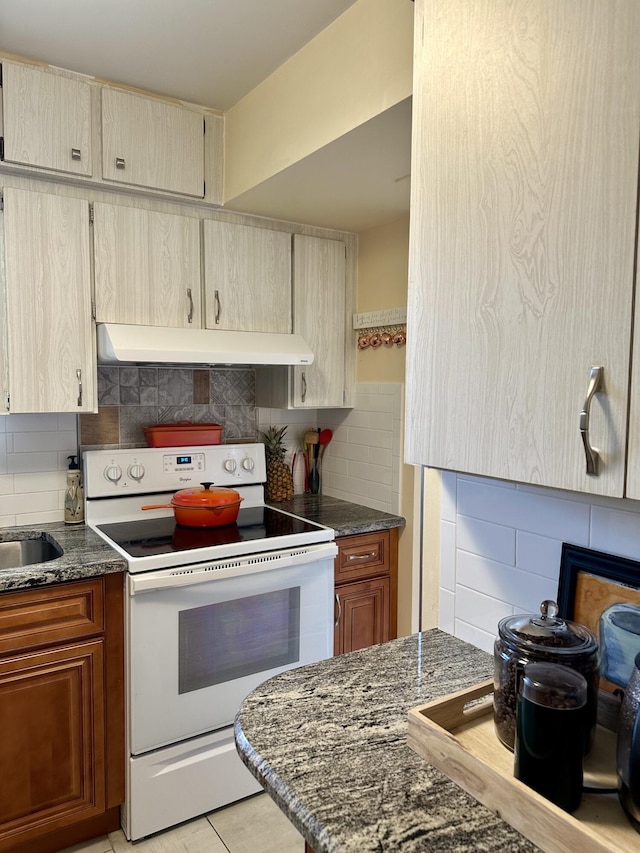 1957 SW Palm City Rd Unit B, Stuart, FL 34994 - kitchen featuring electric range, under cabinet range hood, backsplash, and dark stone countertops