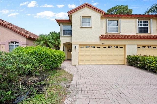 1047 Via Jardin, Riviera Beach, FL 33418 - mediterranean / spanish home featuring an attached garage, stucco siding, decorative driveway, and a tiled roof