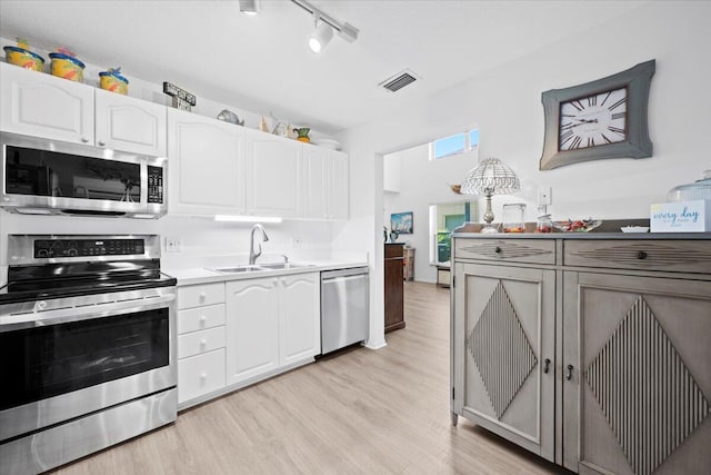 1047 Via Jardin, Riviera Beach, FL 33418 - kitchen featuring stainless steel appliances, light wood-style flooring, white cabinets, and track lighting