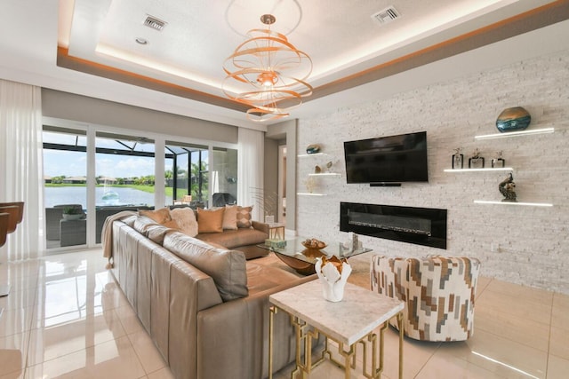 10948 SW Ivory Springs Ln, Port Saint Lucie, FL 34987 - living area with light tile patterned flooring, a glass covered fireplace, a raised ceiling, and a chandelier