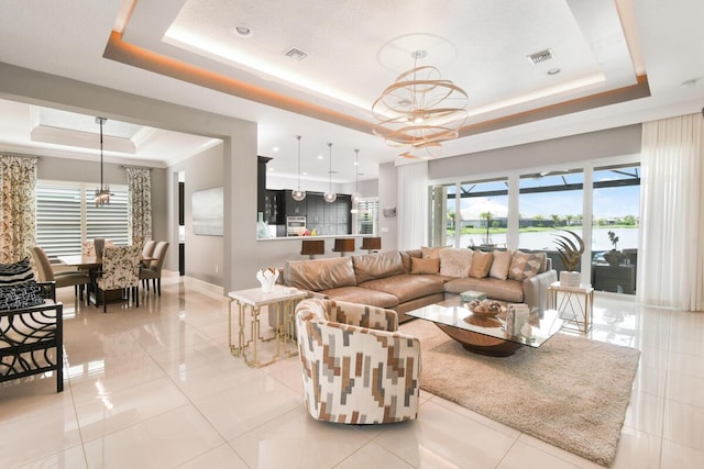 10948 SW Ivory Springs Ln, Port Saint Lucie, FL 34987 - living room featuring a tray ceiling, a chandelier, light tile patterned flooring, and a water view