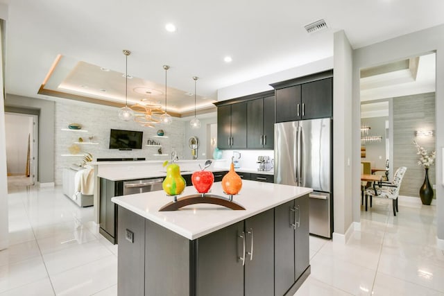 10948 SW Ivory Springs Ln, Port Saint Lucie, FL 34987 - kitchen with appliances with stainless steel finishes, a raised ceiling, a kitchen island with sink, light tile patterned floors, and recessed lighting