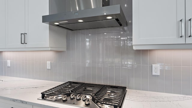 2165 SE Mosaic Blvd, Port Saint Lucie, FL 34984 - kitchen view of extractor fan, stainless steel gas stovetop, tasteful backsplash, and white cabinetry