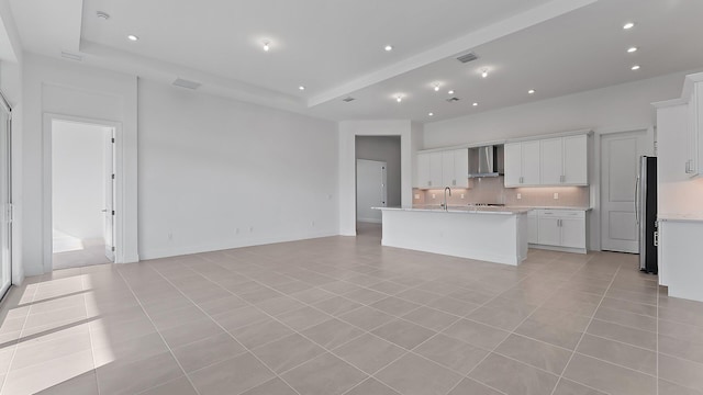 2165 SE Mosaic Blvd, Port Saint Lucie, FL 34984 - kitchen with wall chimney range hood, backsplash, light countertops, open floor plan, and light tile patterned floors