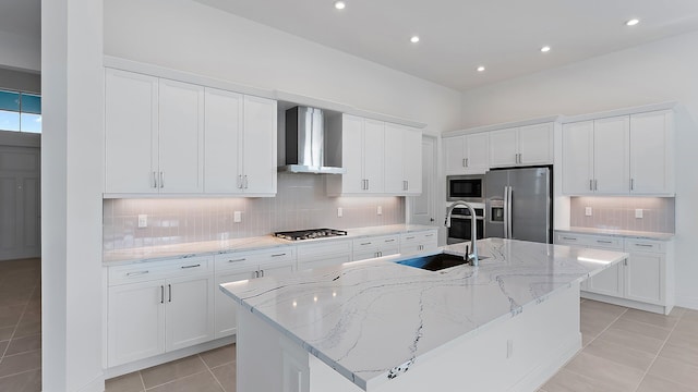 2165 SE Mosaic Blvd, Port Saint Lucie, FL 34984 - kitchen with appliances with stainless steel finishes, wall chimney exhaust hood, light tile patterned flooring, backsplash, and a center island with sink