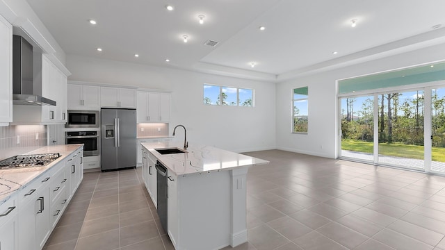 2165 SE Mosaic Blvd, Port Saint Lucie, FL 34984 - kitchen with stainless steel appliances, wall chimney exhaust hood, light tile patterned flooring, white cabinetry, and light stone countertops