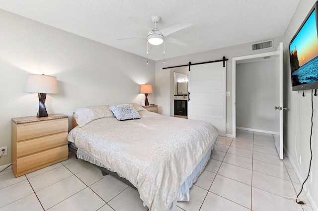 15451 Pembridge Dr Unit 207, Delray Beach, FL 33484 - bedroom with a barn door, light tile patterned floors, a textured ceiling, and ceiling fan