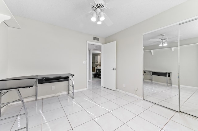 15451 Pembridge Dr Unit 207, Delray Beach, FL 33484 - unfurnished bedroom featuring a closet, a ceiling fan, tile patterned floors, and a textured ceiling