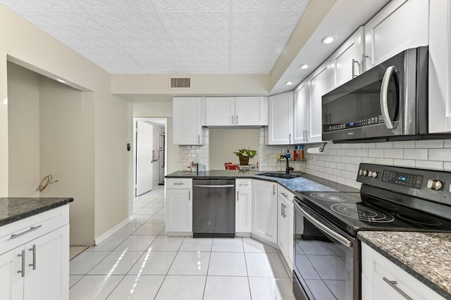 15451 Pembridge Dr Unit 207, Delray Beach, FL 33484 - kitchen with stainless steel appliances, decorative backsplash, white cabinetry, dark stone countertops, and recessed lighting