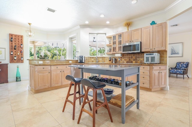15687 83rd Way N, Palm Beach Gardens, FL 33418 - kitchen with stainless steel microwave, light brown cabinetry, backsplash, recessed lighting, and crown molding