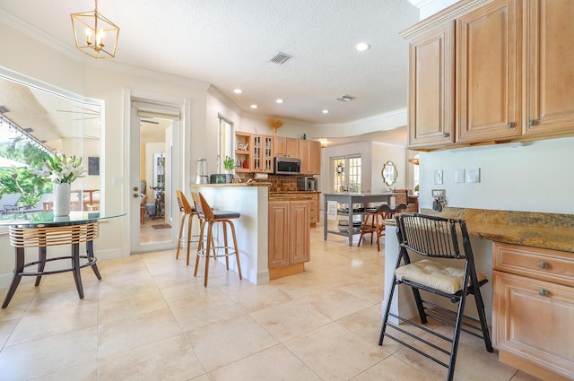 15687 83rd Way N, Palm Beach Gardens, FL 33418 - kitchen with stainless steel microwave, a kitchen breakfast bar, ornamental molding, a peninsula, and light tile patterned flooring