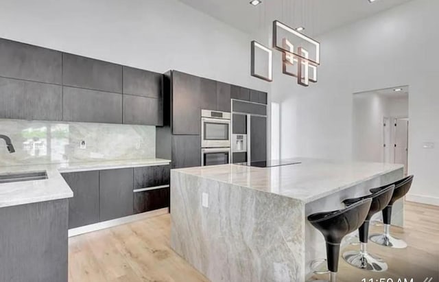 2299 NW 55th St, Boca Raton, FL 33496 - kitchen with modern cabinets, a high ceiling, a large island, light wood finished floors, and stainless steel double oven