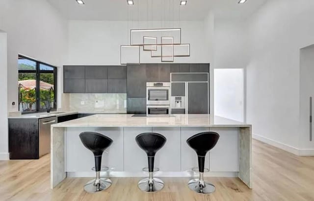2299 NW 55th St, Boca Raton, FL 33496 - kitchen with appliances with stainless steel finishes, modern cabinets, light countertops, light wood-type flooring, and a breakfast bar
