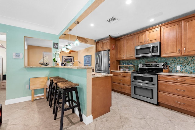 1098 SW 2nd St, Boca Raton, FL 33486 - kitchen featuring appliances with stainless steel finishes, brown cabinetry, a breakfast bar area, and recessed lighting