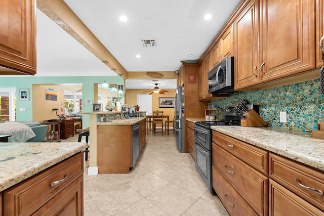 1098 SW 2nd St, Boca Raton, FL 33486 - kitchen with stainless steel appliances, brown cabinetry, tasteful backsplash, light stone counters, and recessed lighting