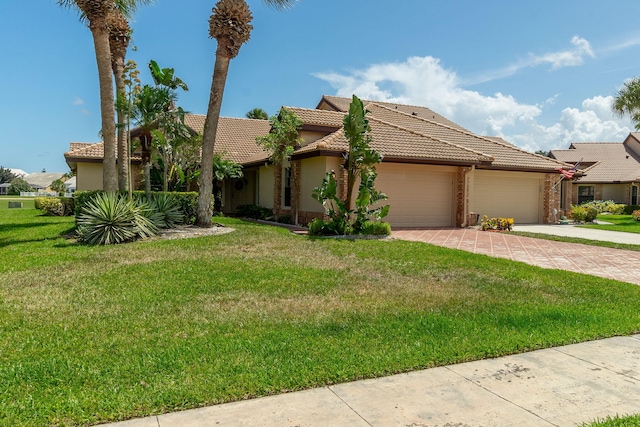 8057 Cassia Dr, Boynton Beach, FL 33472 - view of front of house featuring a garage, driveway, a tile roof, a front lawn, and stucco siding