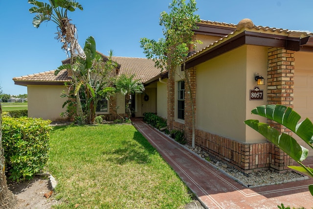 8057 Cassia Dr, Boynton Beach, FL 33472 - view of property exterior featuring stucco siding, a tile roof, a yard, and an attached garage