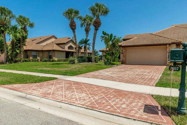 8057 Cassia Dr, Boynton Beach, FL 33472 - view of front of home featuring a tile roof, a front yard, a garage, stucco siding, and driveway